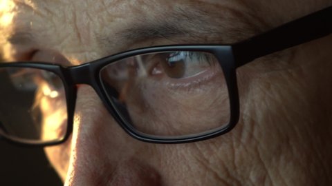 Close-up of the focused .of a businessman wearing computer glasses, looking at a reflective PC screen