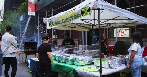 New York, New York United States - May 5, 2022: Street Food Festival in the city. Tent stand selling Jamaican Jerk Chicken. Customers wait for order.