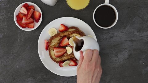 Pouring Syrup on French Toast with Strawberries and Bananas