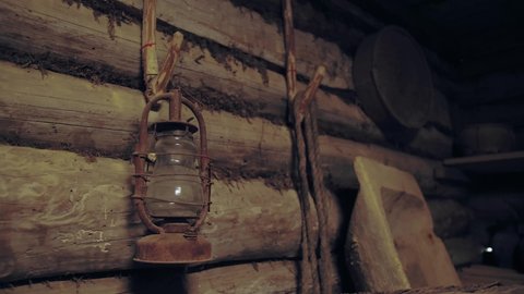 An old rusty kerosene lamp hangs on the wall. Vintage lamp on the background of a wooden wall.