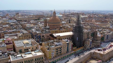 Aerial 4K footage of a drone flight over of Basilica Lady of Mount Carmel church, St. Paul's Cathedral in the old town of Valetta, Malta. Roofs of Malta capital from above on a sunny day