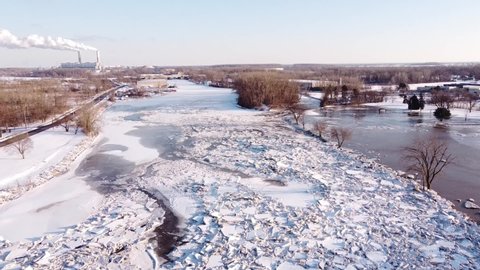 Foreground Ice Blockage On The River Raisin Of Monroe City, Michigan, USA Overlooking The Monroe Coal Power Plant. Aerial Pullback