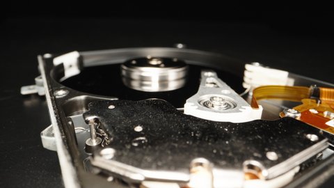 Disassembled computer hard drive, on a black background. Repair. Dolly slider extreme close-up. Laowa Probe