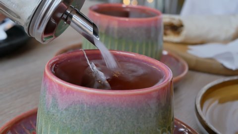 pour granulated sugar into a mug of tea using a glass sugar bowl with a dispenser. Close-up. Slow motion.