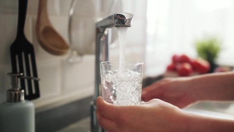 Woman pouring a tap water in glass, concept of pure drinking water.: film stockowy