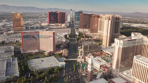 Aerial 4K view Las Vegas Strip boulevard with busy traffic at early sunset in golden light. Hotels with casinos, Venetian, Palazzo resorts day view from helicopter tour. Las Vegas Strip, USA, Apr 2022