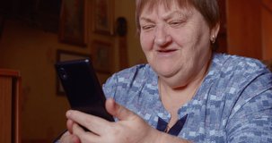 Senior woman watch funny video on smartphone. Elderly female person communicate by cell phone