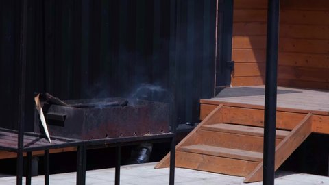 A smoking brazier on the background of a modern stylish house. Preparation for frying meat