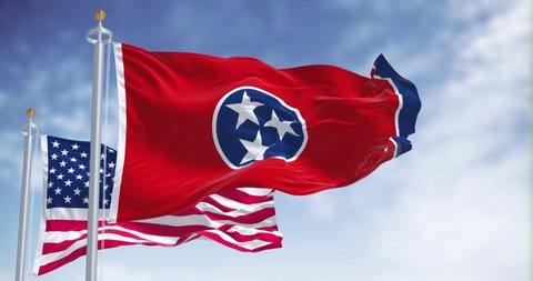 The Tennessee state flag waving along with the national flag of the United States of America. Tennessee is a state in the Southeastern region of the United States