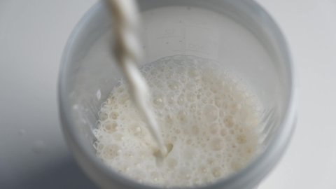 Making protein cocktail. Adding milk for protein powder into the shaker bottle