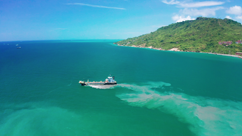 Aerial view of cargo ship leaves the side leaving a mud, Pollution, brown Muddy water behind it. Royalty-Free Stock Footage #1090181723