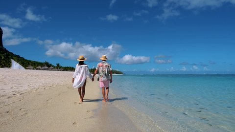 Le Morne beach Mauritius Tropical beach with palm trees and white sand blue ocean couple men and woman walking at the beach during vacation