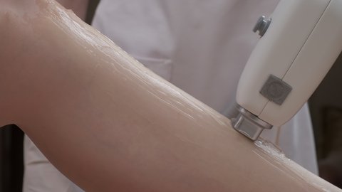 Close-up of leg laser epilation procedure while laser hair removal machine is used by specialist