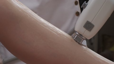 Close-up of leg laser epilation procedure while laser hair removal machine is used by specialist