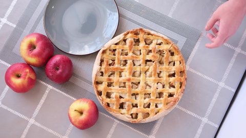 Apple pice cake preparation series - woman taking slicie of a traditional pie - top view