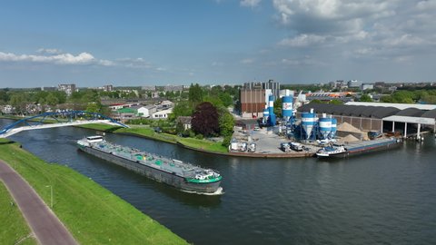 ZWOLLE, NETHERLANDS - MAY 6, 2022: Freight ship barge sailing on the Zwolle-IJssel canal in the port of Zwolle seen from above during springtime.