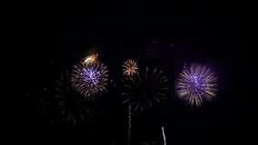 Bright flashes of holiday salute in the night black sky. Sparkling fireworks explosions and falling lights. Real celebration fireworks background. HD video, time lapse