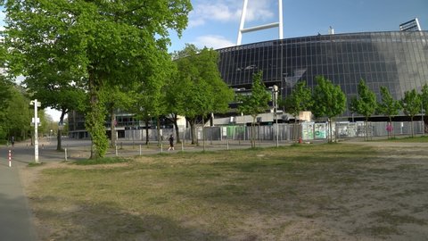 2022-05-03 Bremen, Germany - 4k pan right establishing shot of Weserstadion stadium under blue sky during spring with green leaves around.