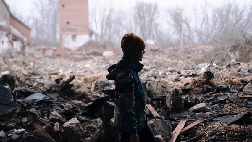 A boy walks through the ruins of destroyed houses under the falling snow. He looks sad and he's looking for someone. Royalty-Free Stock Footage #1090188039