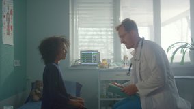 African teen girl visit doctor sitting couch in hospital office. Professional pediatrician talking with preteen patient at medical consultation. Positive physician asking health complaints young kid. - Powered by Shutterstock - Get 15% off with code: PIKWIZARD15