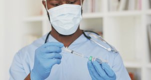 Video of african american male doctor in face mask preparing vaccine. health, medicine and medical profession concept.