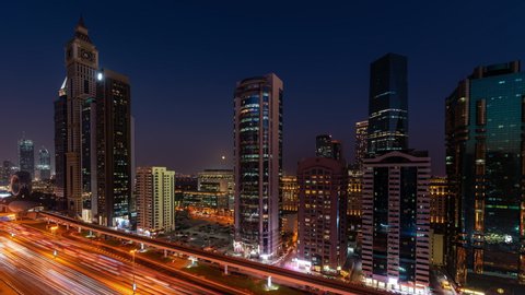 Dubai, United Arab Emirates - October 20 2021: Time Lapse of a sunset at Sheikh Zayed Road in Dubai with the iconic skyscrabers and a full moon rising