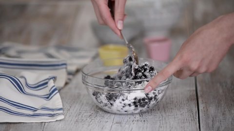 Female hands mixing blackcurrant with cornstarch.