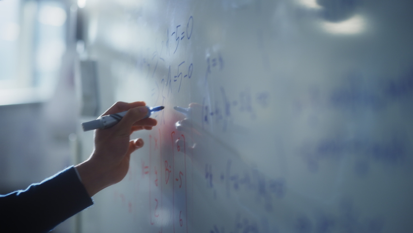 Man Draws Charts and Write Mathematical Formulas on a Whiteboard with Blue Marker Pen. Science and Education Concept. Macro Follow Shot