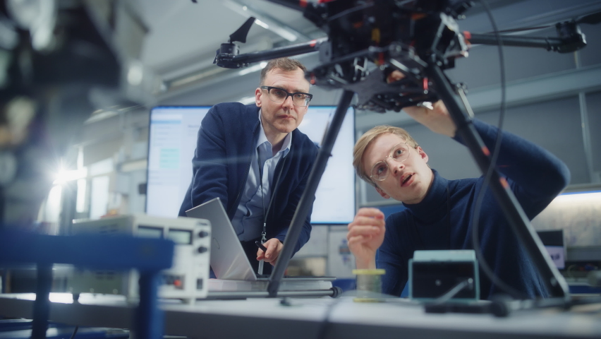 Chief Engineer Look at Drone Attentively While Discussing Design with Promising Scientist. Manufacturing Facility that Creates Great Products. Slow Motion Royalty-Free Stock Footage #1090193381