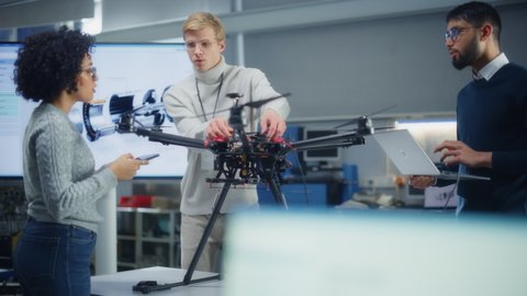Diverse Aviation Engineers Building, Sets Up, Configuring and Testing Drones while Work at Factory. Aviation Industry and Startup Concept. Slow Motion