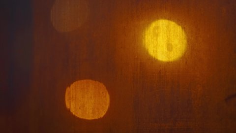 the texture of a fogged window with warm lights of lanterns in the background close-up