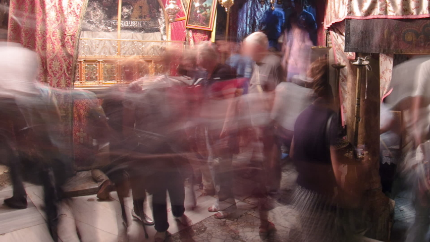 Church of the Nativity interior with altar and icon lamps hanging on long chain in Bethlehem timelapse. People inside