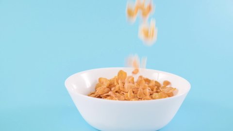 Cornflakes. Dry breakfasts are poured into a bowl. Vitamin food for children and adults. Slow motion food. Bright colours. High quality FullHD footage