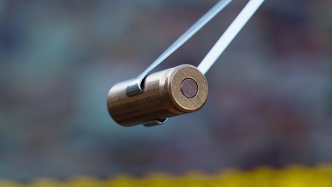 Photorealistic animation of pistol bullet shell held by tweezers. Examine evidence of a crime. Symbol of crime, corruption, violence, mischief. A metal bullet fired from a rifle. Pistol shooting. Ammo