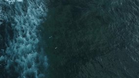 aerial view of drone recording surfers catching waves in the atlantic oceaon