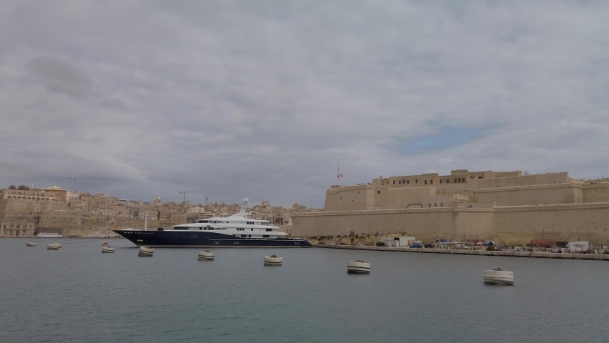 Sailing past Vittoriosa waterfront with boats moored in the waterway