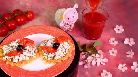 Vegetarian sandwich with cottage cheese, dill, tomatoes and olives, rotate slowly. Pouring tomato juice in drinking glass. Pink light.