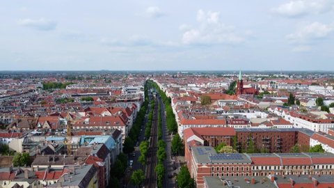 Go to work, panorama of long wide street in the middle of Berlin. Gorgeous aerial view flight slowly tilt up drone footage of Prenzlauer Berg Schönauer Allee Spring 2022. Cinematic by Philipp Marnitz