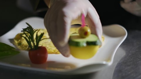 The chef in the restaurant kitchen prepares omelet plate. slow motion,close up. 4K Hot Scrambled Eggs Food with Vegetable Salad on a Plate in the Kitchen