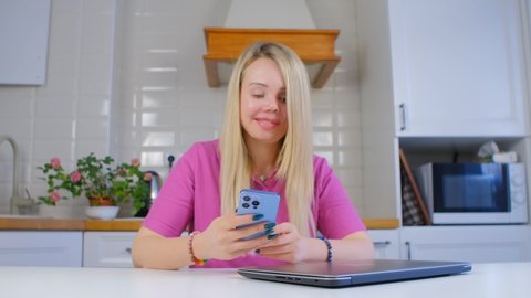 Domestic violence victim using mobile phone. Young Ukrainian woman with prosthetic eye and facial scars browsing internet news feed on modern smartphone