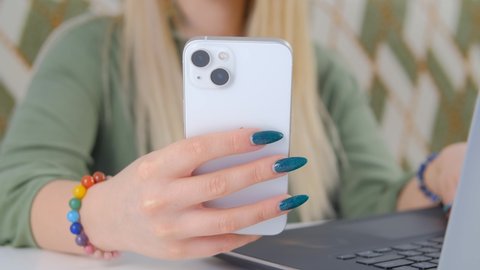Young girl with painted long nails using modern mobile phone. White woman browsing apps on modern white smartphone