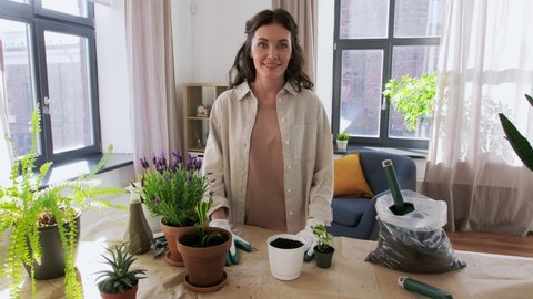 blogging, gardening and housework concept - happy woman or blogger planting pot flowers and recording tutorial video at home