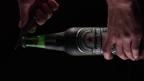 Zaporizhzha, Ukraine - May 11 2022: Heineken opening. Beautiful sound. Opening the cap of a beer. The ASMR sound of opening a beer. Beer bottle on black background.