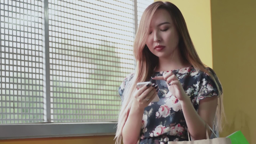 A young woman of Asian appearance is browsing websites on her phone