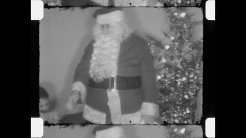 1955 Chicago, IL. Man in Santa Suit visit with children in front of tinsel Christmas tree. Young boys and girls shake Santa's hand excited to meet Jolly Saint Nick. 4k Overscan of Vintage Home Movies.