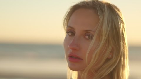 Portrait of a blonde at sunset on the ocean . Close-up of a sexy girl. The model looks into the camera. Beautiful girl slow motion