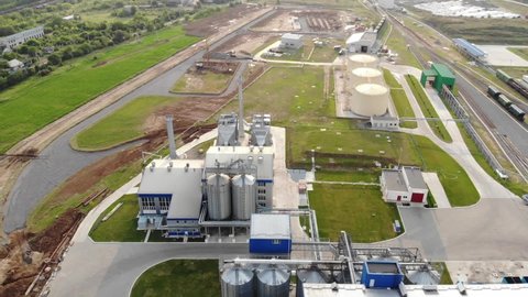 Metal tanks of the elevator. Grain drying complex in the open air. Commercial granaries. Steel warehouse for agricultural crops. Aerial view.