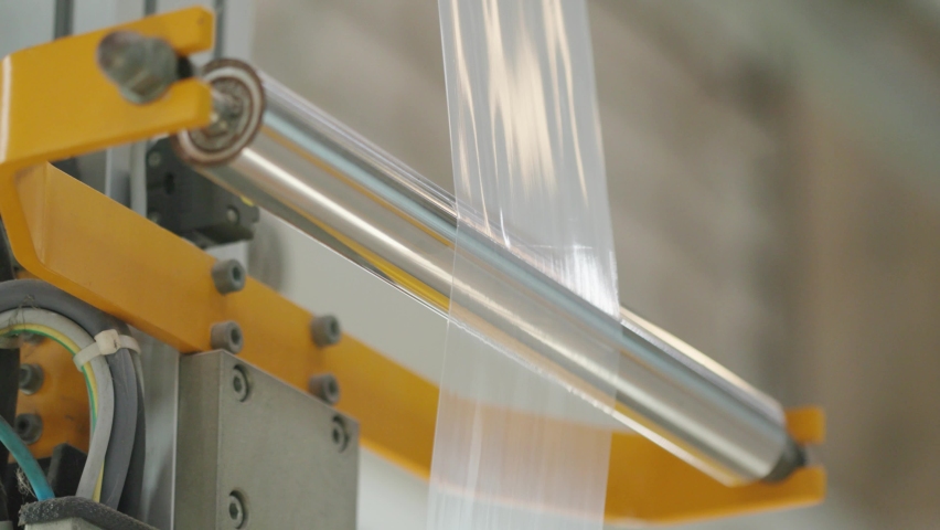 Multilayer plastic film rolling on the machine at the factory. Goods and products packaging, industrial automation, plastic themes. Sealability. Royalty-Free Stock Footage #1090211659