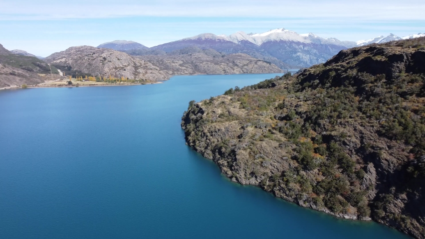 Top aerial drone panoramic view Beautiful snowy mountains landscape and a cristal clear river along gravel road Carretera Austral in southern Patagonia, Chile