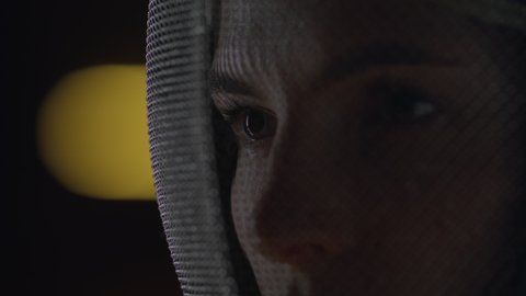 Extreme close up portrait of female fencer in a protective mask, preparing for the fight
